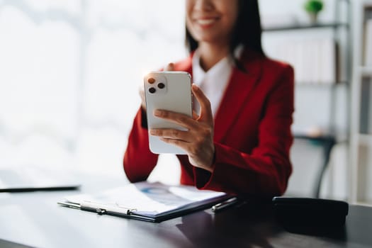 Portrait of beautiful young businesswoman standing smiling and using smartphone.