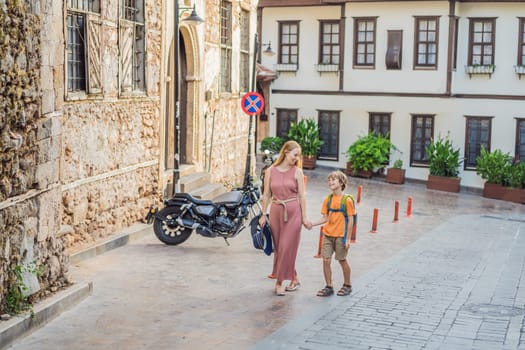 Mom and son tourists in Old town Kaleici in Antalya. Turkiye. Panoramic view of Antalya Old Town port, Taurus mountains and Mediterrranean Sea, Turkey. Traveling with kids concept.