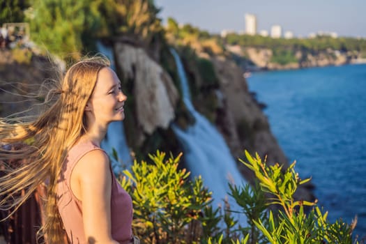 Beautiful woman with long hair on the background of Duden waterfall in Antalya. Famous places of Turkey. Lower Duden Falls drop off a rocky cliff falling from about 40 m into the Mediterranean Sea in amazing water clouds. Tourism and travel destination photo in Antalya, Turkey. Turkiye.