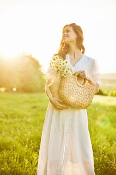 a laughing woman with a full basket of daisies stands in a light dress against the backdrop of a sunset in a field. High quality photo
