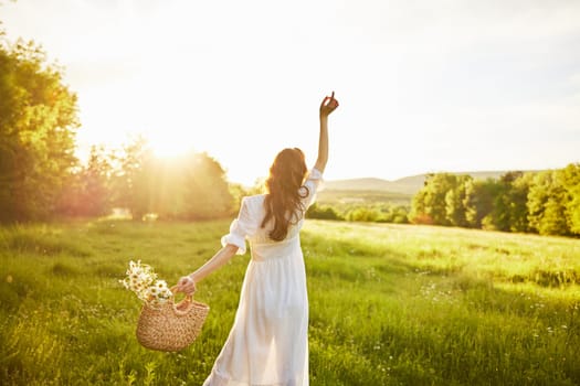 a girl in a long light dress stands in a field during sunset with her back to the camera. Full length photo. High quality photo