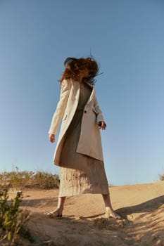 stylish woman in a light jacket posing in nature covering her face with hair. High quality photo