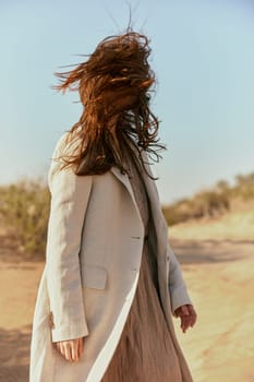 portrait of a woman in a light jacket with hair covering her face from the wind. High quality photo