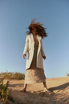 stylish woman in a light jacket posing in nature covering her face with hair. High quality photo