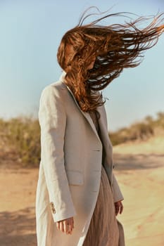 portrait of a woman in a light jacket with hair covering her face from the wind. High quality photo