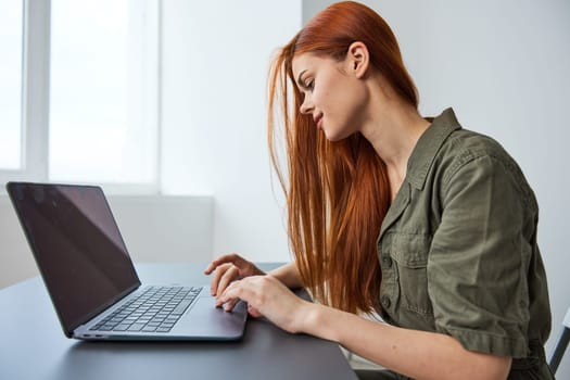 woman in bright office typing puzzled at laptop while working full time. High quality photo