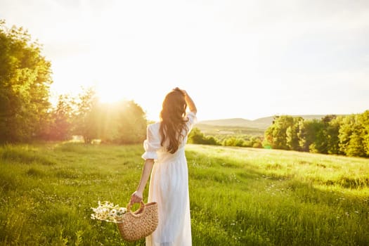 a girl in a long light dress stands in a field during sunset with her back to the camera. Full length photo. High quality photo