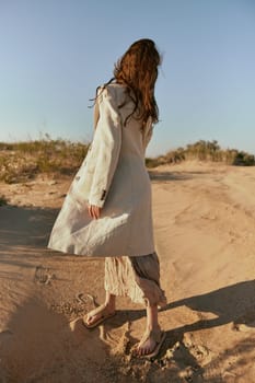 stylish woman in a light jacket posing on the sand, turning away from the camera. High quality photo