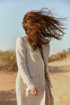 portrait of a woman in a light jacket with hair covering her face from the wind. High quality photo