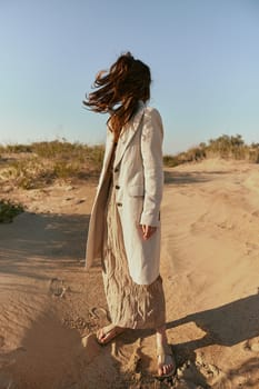 stylishly dressed woman stands posing in the desert in windy weather. High quality photo