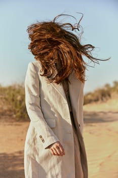 portrait of a woman in a light jacket with hair covering her face from the wind. High quality photo