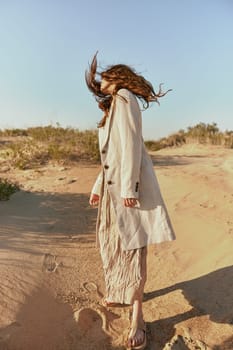 stylishly dressed woman stands posing in the desert in windy weather. High quality photo