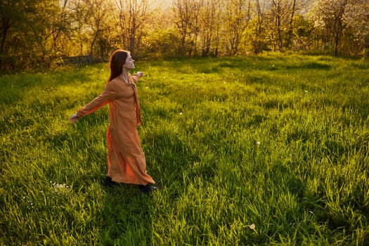 a joyful woman runs through a green field with her hands behind her back, enjoying a warm summer day and nature during the sunset. Horizontal photography in nature. High quality photo