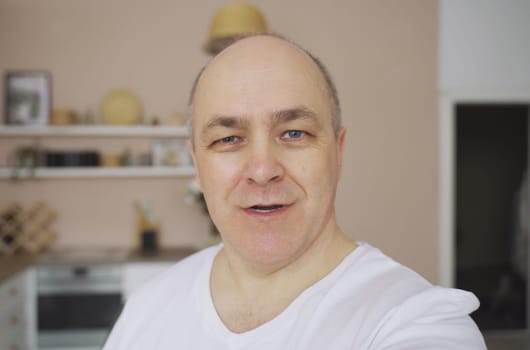 Smiling male blogger taking a selfie or video call from his apartment.