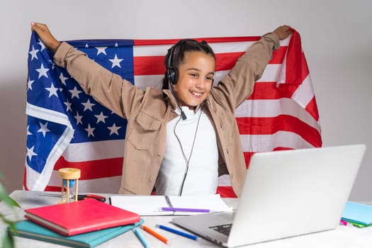 Little boy cheering with American flag. Education online on laptop computer. Pupil in class.