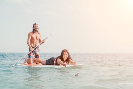 Silhouette of woman standing, surfing on SUP board, confident paddling through water surface. Idyllic sunset or sunrise. Sports active lifestyle at sea or river.