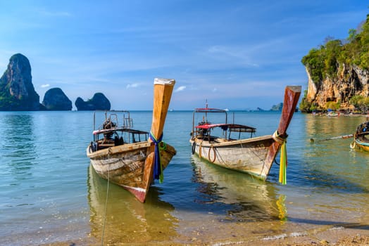 KRABI, THAILAND- MARCH 2018: Long tail boat on tropical beach with palms, Tonsai Bay, Railay Beach, Ao Nang, Krabi, Thailand.