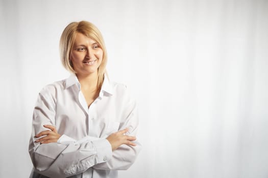 Portrait of a pretty blonde smiling woman posing on white background. Happy girl model in white shirt posing in studio. Copy space
