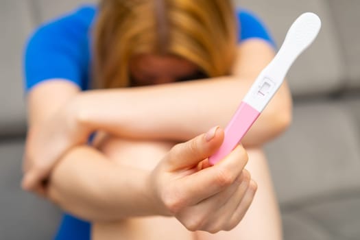 Upset woman holding a negative pregnancy test. Strong wish to have a baby and infertility
