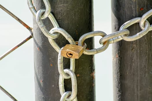 A lock and chain on Metal Fence that links of a gate.
