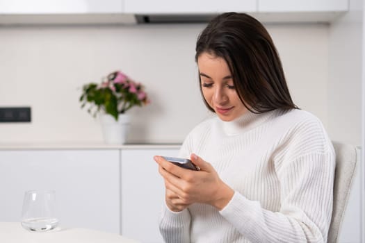 Dreamy millennial girl checking social media holding smartphone in her hands.