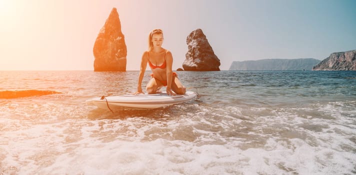 Close up shot of beautiful young caucasian woman with black hair and freckles looking at camera and smiling. Cute woman portrait in a pink bikini posing on a volcanic rock high above the sea