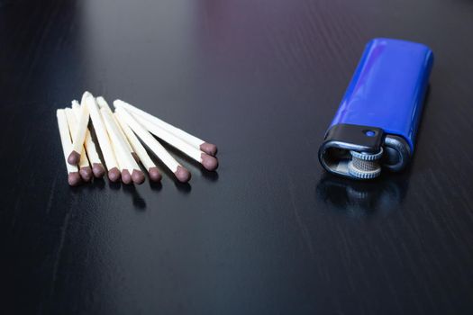 Pile of matches and lighter on a black wooden table