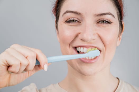 Close-up portrait of caucasian woman brushing her teeth. The girl performs the morning oral hygiene procedure.