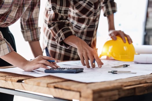 Architect and Engineer working with blueprints for architectural plan, engineer sketching a construction project, green energy concept.