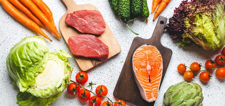 Assorted food raw products: vegetables, beef meat steak, fish salmon fillet on wooden cutting boards, white rustic table top view. Healthy food ingredients background, diet and balanced nutrition