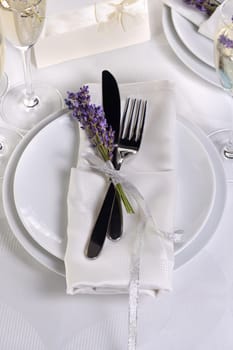 Lavender mood. Dining table in Provence style, with Lavender Champagne, folded napkin with cutlery, decorated with fresh lavender. Detail of the wedding dinner. Wedding theme ideas.