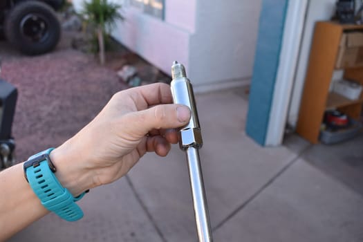 Hand on Deep Well Socket with Spark Plug in Driveway. High quality photo