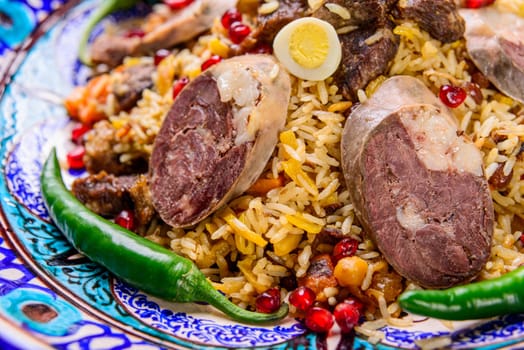 A closeup of an appetizing Uzbek national dish Plov, Pilaf made of rice and meat served with peppers