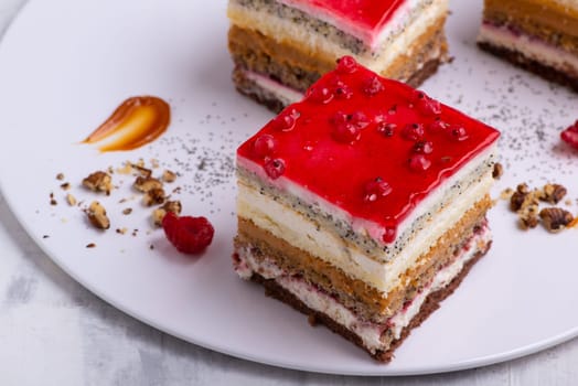 An appetizing dessert with slices of cakes with raspberry and nuts