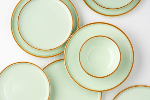 A set of pastel green ceramic tableware with orange outlines. Top view