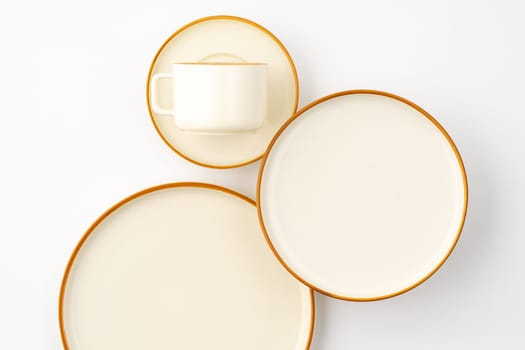 A set of white and brown ceramic plate and cup on a white background. Top view