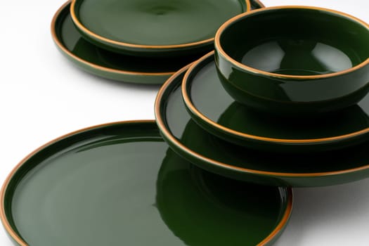 A set of green ceramic plates and bowl on a white background