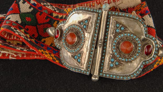 An antique belt in traditional red, patterns with precious stones isolated on a black background