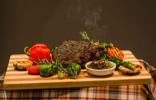 Closeup of serving table for lunch, fried meat, vegetables, green pepper and grilled potatoes on wooden board