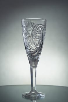 A vertical shot of an empty champagne glass on a grey background
