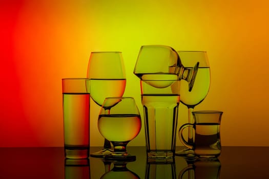 Some glasses for different drinks stacked on a colorful background