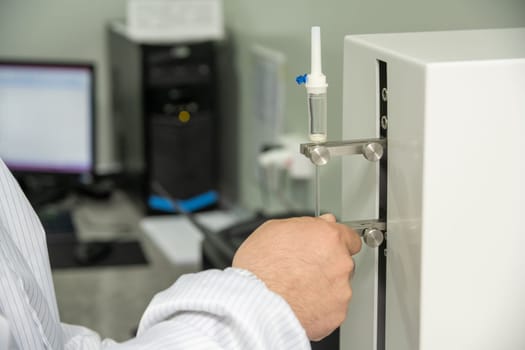 A closeup shot of hands working on a machine in a medical production warehouse for syringes