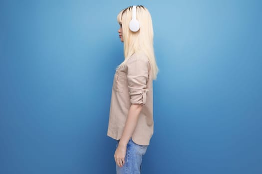 portrait of a young energetic blond woman in white headphones.