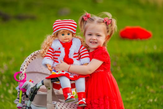 The girl plays with a doll in nature, holding her in her arms