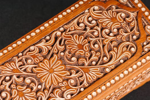 The artistic wood carving on the casket on the black background. Central Asia, Uzbekistan, close-up
