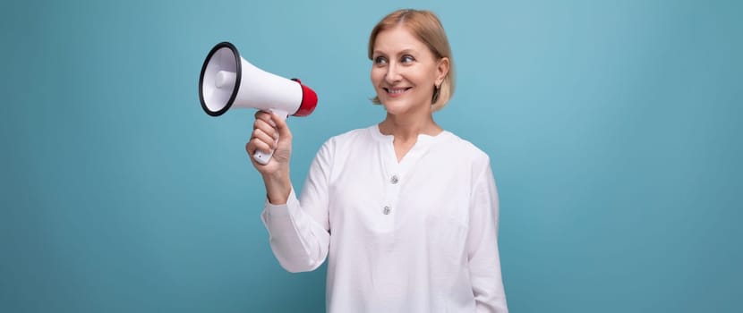 mature woman with blond hairstyle speaks important news with loudspeaker.