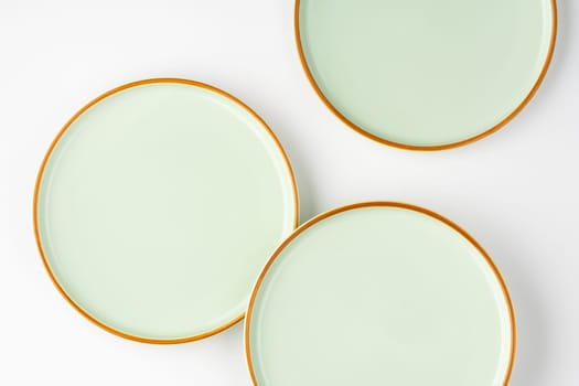 A set of pastel green ceramic tableware with orange outlines. Top view