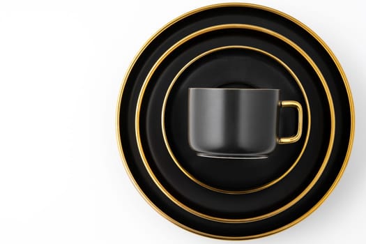 A set of black and golden ceramic plates and cup on a white background. Top view