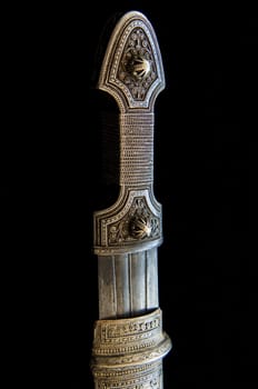 The handle of an antique dagger with artistic chasing and engraving on a black background