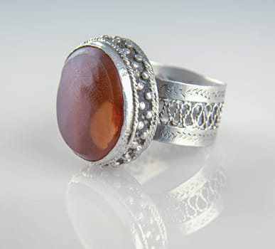 A Vintage, silver ring with a precious, big stone isolated on a reflective background